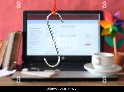 phishing dei dati, un grande gancio sul computer portatile che mostra un sito web di phishing fittizio, sfocato in background Foto Stock