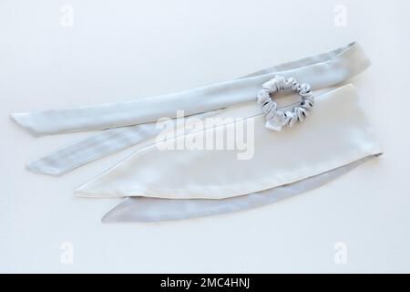 cravatte a fascia argento-seta-raso. fasce elastiche moda per capelli su sfondo bianco vista dall'alto Foto Stock