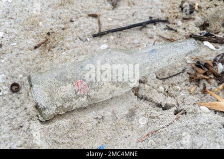 bottiglie di plastica di vetro sul bordo di una spiaggia di sabbia bianca nel mezzo del paesaggio naturale Foto Stock