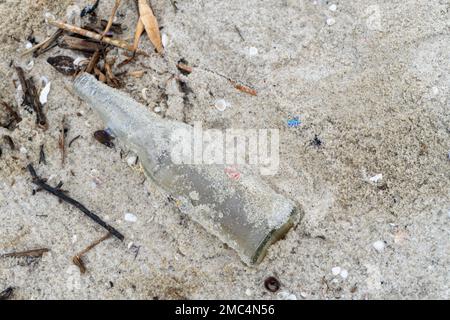 bottiglie di plastica di vetro sul bordo di una spiaggia di sabbia bianca nel mezzo del paesaggio naturale Foto Stock