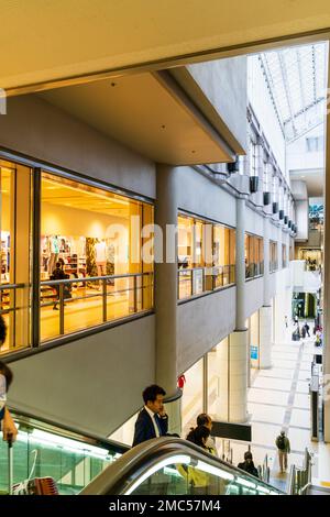 Tokyo Haneda airport terminal uno interno. Primo piano vista di persone sulla scala mobile dal primo piano area dello shopping al piano terra. Foto Stock