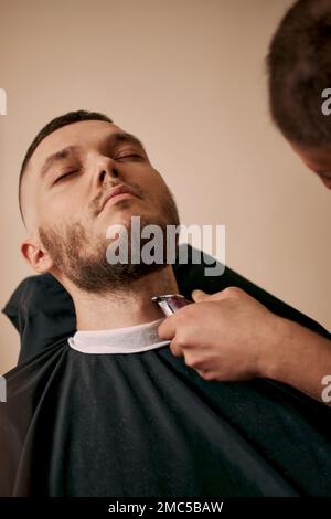 Barber rifinisci i capelli con il regolacapelli sul bel barbiere. Foto Stock