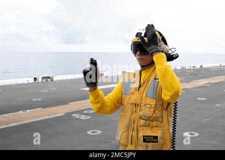 220625-N-XN177-1063 MARE DELLE FILIPPINE (25 giugno 2022) – Aviation Boatswain’s Mate 3rd Class Carla Rivera, da Baldwin Park, California, segnala all'equipaggio durante le operazioni di volo a bordo del vettore d'assalto anfibio USS Tripoli (LHA 7), 25 giugno 2022. Tripoli opera nell'area delle operazioni della flotta 7th degli Stati Uniti per migliorare l'interoperabilità con alleati e partner e fungere da pronta forza di risposta per difendere la pace e mantenere la stabilità nella regione dell'Indo-Pacifico. Foto Stock