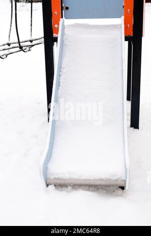 scivolo vuoto coperto di neve sulla strada, sul parco giochi Foto Stock