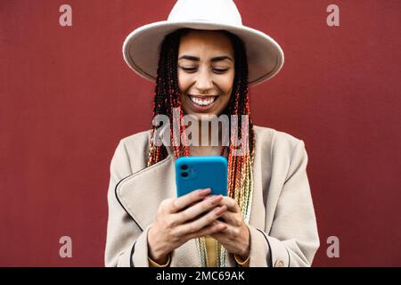 Felice giovane ragazza africana che si diverte utilizzando smartphone mobile all'aperto Foto Stock