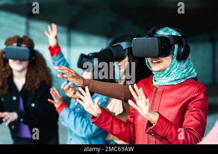 Giovani ragazze multirazziali che utilizzano occhiali futuristici per la realtà virtuale - tecnologia e concetto di metaverse Foto Stock