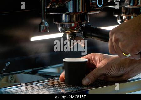 Barista che prepara il caffè davanti alla macchina da caffè, barista che prepara l'espresso a mano Foto Stock