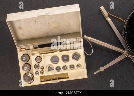 Set di pesi metallici per vecchie bilance per gioielli su ardesia, macro, vista dall'alto Foto Stock