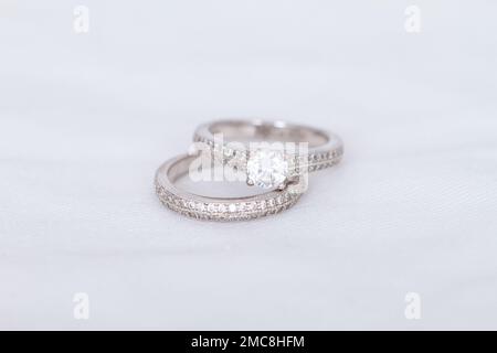 Primo piano di due anelli d'oro bianco / argento, uno con una grande pietra a diamante, e l'altro una banda con borchie. Foto Stock