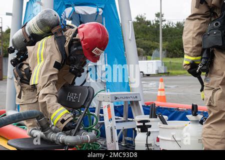 Un vigile del fuoco con installazioni di corpi marini Pacific Fire and Emergency Services fornisce acqua alla linea di decontaminazione durante un esercizio di formazione sui materiali pericolosi a Camp Hansen, Okinawa, Giappone, 27 giugno 2022. La formazione HAZMAT ha incluso più vittime simulate in un ambiente pericoloso, neutralizzando al contempo l'area contaminata. MCIPAC F&ES è un reparto antincendio regionale che gestisce otto stazioni antincendio in tutto il Giappone e fornisce servizi alle installazioni, tra cui antincendio, soccorso tecnico, materiali pericolosi, pronto soccorso, protezione antincendio e prevenzione. Foto Stock