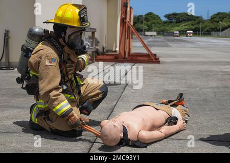 Un vigile del fuoco con le installazioni del corpo Marino Pacific Fire and Emergency Services assiste una vittima simulata durante un esercizio di addestramento sui materiali pericolosi a Camp Hansen, Okinawa, Giappone, 27 giugno 2022. La formazione HAZMAT ha incluso più vittime simulate in un ambiente pericoloso, neutralizzando al contempo l'area contaminata. MCIPAC F&ES è un reparto antincendio regionale che gestisce otto stazioni antincendio in tutto il Giappone e fornisce servizi alle installazioni, tra cui antincendio, soccorso tecnico, materiali pericolosi, pronto soccorso, protezione antincendio e prevenzione. Foto Stock