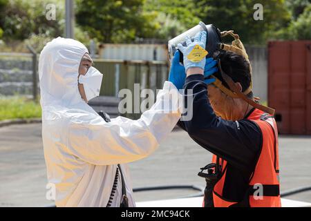 Vigili del fuoco con installazioni di corpi marini Pacific Fire ed Emergency rimuovono la loro attrezzatura dopo un esercizio di addestramento sui materiali pericolosi a Camp Hansen, Okinawa, Giappone, 27 giugno 2022. La formazione HAZMAT ha incluso più vittime simulate in un ambiente pericoloso, neutralizzando al contempo l'area contaminata. MCIPAC F&ES è un reparto antincendio regionale che gestisce otto stazioni antincendio in tutto il Giappone e fornisce servizi alle installazioni, tra cui antincendio, soccorso tecnico, materiali pericolosi, pronto soccorso, protezione antincendio e prevenzione. Foto Stock