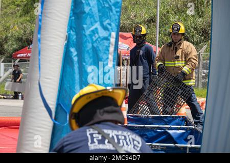 Vigili del fuoco e ingegneri con installazioni del corpo marino Pacific Fire and Emergency Services costruiscono una linea di decontaminazione durante un esercizio di formazione sui materiali pericolosi a Camp Hansen, Okinawa, Giappone, 27 giugno 2022. La formazione HAZMAT ha incluso più vittime simulate in un ambiente pericoloso, neutralizzando al contempo l'area contaminata. MCIPAC F&ES è un reparto antincendio regionale che gestisce otto stazioni antincendio in tutto il Giappone e fornisce servizi alle installazioni, tra cui antincendio, soccorso tecnico, materiali pericolosi, pronto soccorso, protezione antincendio e prevenzione. Foto Stock