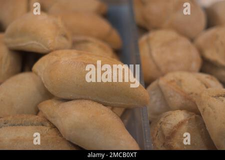 Un espositore pieno di ciambelle. Un negozio con deliziosi, croccanti, panini freschi all'interno. Focaccine appena sfornate in una panetteria. Produzione artigianale di prodotti da forno Foto Stock