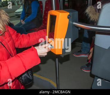 Giovane donna alla moda che utilizza una macchina punzonatrice per biglietti nei trasporti pubblici. La ragazza prende a pugno il biglietto. Foto Stock