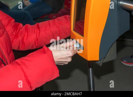 Giovane donna alla moda che utilizza una macchina punzonatrice per biglietti nei trasporti pubblici. La ragazza prende a pugno il biglietto. Foto Stock