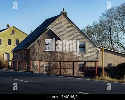 Rivestimento in amianto sulla parete esterna di un edificio residenziale. Vecchia facciata nella Germania orientale. Lastre di cemento grigie con il materiale in fibra pericoloso. Foto Stock