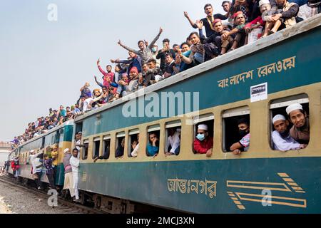 Dhaka, Bangladesh. 22nd Jan, 2023. I devoti musulmani viaggiano su treni rischiosi sovraffollati dopo aver assistito all'Akheri Munajat o alle preghiere finali, al Biswa Ijtema di Tongi, Dhaka, Bangladesh. Gli abitanti del luogo affrontano il viaggio salendo, aggrappandosi e clambering lungo i tetti delle locomotive. Senza posti a sedere all'interno, molti pendolari decidono di correre il rischio e di scegliere una vista sul tetto per il loro viaggio fuori dalla città di Dhaka. Credit: Joy Saha/Alamy Live News Foto Stock