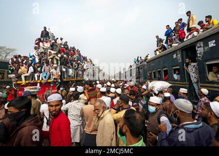 Dhaka, Bangladesh. 22nd Jan, 2023. I devoti musulmani viaggiano su treni rischiosi sovraffollati dopo aver assistito all'Akheri Munajat o alle preghiere finali, al Biswa Ijtema di Tongi, Dhaka, Bangladesh. Gli abitanti del luogo affrontano il viaggio salendo, aggrappandosi e clambering lungo i tetti delle locomotive. Senza posti a sedere all'interno, molti pendolari decidono di correre il rischio e di scegliere una vista sul tetto per il loro viaggio fuori dalla città di Dhaka. Credit: Joy Saha/Alamy Live News Foto Stock