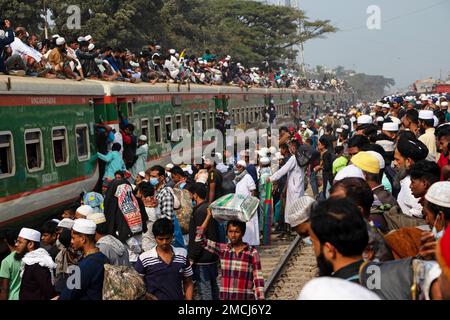 Dhaka, Bangladesh. 22nd Jan, 2023. I devoti musulmani viaggiano su treni rischiosi sovraffollati dopo aver assistito all'Akheri Munajat o alle preghiere finali, al Biswa Ijtema di Tongi, Dhaka, Bangladesh. Gli abitanti del luogo affrontano il viaggio salendo, aggrappandosi e clambering lungo i tetti delle locomotive. Senza posti a sedere all'interno, molti pendolari decidono di correre il rischio e di scegliere una vista sul tetto per il loro viaggio fuori dalla città di Dhaka. Credit: Joy Saha/Alamy Live News Foto Stock