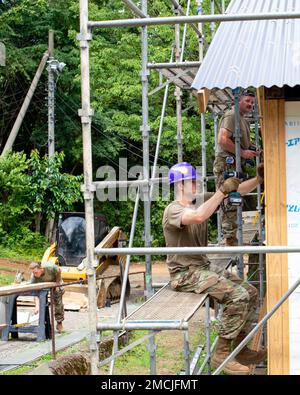 STATI UNITI Air Force Lt. Col. Brett Hansen (primo piano) e Tech. David Berning (background), 133rd ingegnere civile Squadron, appendere al lato esterno durante il restauro di una casa di bagno a Tama Hills Recreation Camp, Giappone, 27 giugno 2022. I progetti interni ed esterni sono stati completati per ripristinare le strutture storiche del Tama Recreation Camp, Tama, Giappone, come parte della formazione annuale. Una volta restaurate le strutture saranno utilizzate dai Boy Scouts. Foto Stock