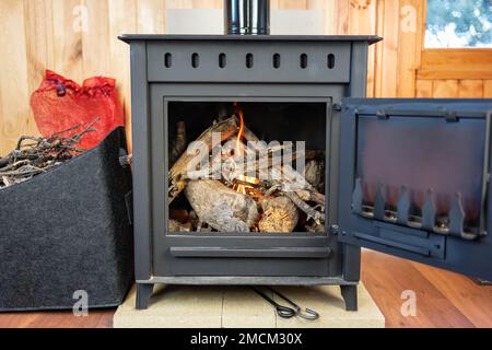 Stufa a legna rustica appena illuminata per riscaldare la casa nel freddo inverno. Foto Stock