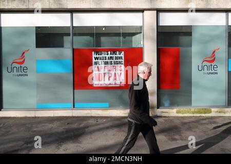 Un uomo che passa davanti a uno slogan presso l'Office of Unite Trade union di Londra, Regno Unito Foto Stock