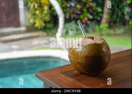 Cocco aperto con paglia di vetro vicino alla piscina Foto Stock