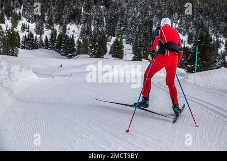 Man in Red Overall pattina da fondo sulle piste da fondo in Svizzera Foto Stock