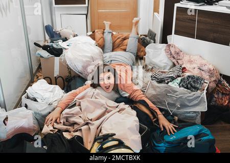 Difficile preparazione al viaggio in famiglia. Spostamento, imballaggio disimballaggio di molte cose, vestiti, valigie, bagaglio a casa in appartamento. Molti pacchetti, bags.M Foto Stock