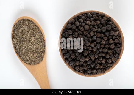 Pepe nero macinato con grani di pepe nero su uno sfondo bianco, vista dall'alto Foto Stock