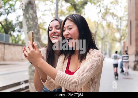 donne che si divertono a guardare contenuti al telefono Foto Stock