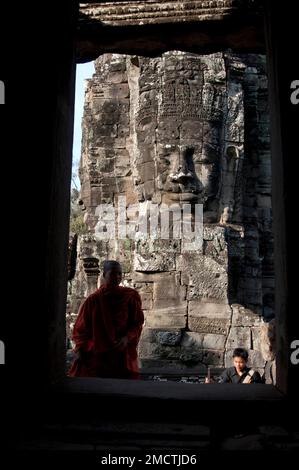 Monaco in porta con grande testa sullo sfondo in tempio, Bayon, Angkor Thom, Angkor Complex, Siem Riep, Cambogia Foto Stock