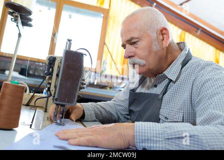 senior che usa la macchina da cucire in fabbrica Foto Stock