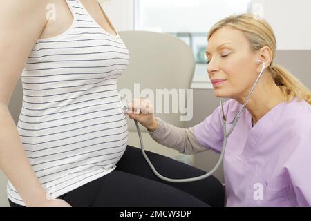 medico ostetrico femminile che misura la pressione sanguigna della donna incinta Foto Stock