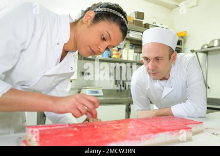 cuoco di pasticceria femmina che tiene vassoio di dolci Foto Stock