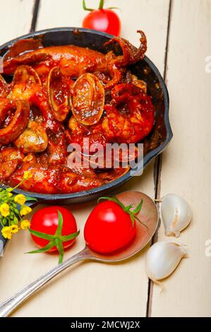 Stufato di pesce fresco preparato su una padella di ferro e tavola bianca rustica in legno Foto Stock