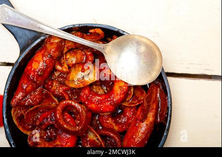 Stufato di pesce fresco preparato su una padella di ferro e tavola bianca rustica in legno Foto Stock