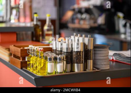 Sul banco di un ristorante si trovano agitatori per sale e pepe e piccole bottiglie di olio d'oliva Foto Stock