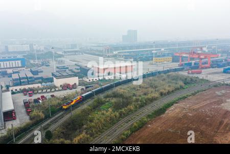 (230122) -- CHONGQING, 22 gennaio 2023 (Xinhua) -- questa foto aerea mostra un treno merci intermodale ferroviario-marittimo che trasporta i contenitori di merci, comprese le automobili, i motocicli, i motori e il carbonato di sodio, Partenza dalla stazione centrale di Tuanjie Village, nella zona sud-occidentale di Chongqing, 22 gennaio 2023. È stato il primo treno merci in uscita della città del nuovo corridoio internazionale di commercio terra-mare nell'anno del coniglio. Le merci sul treno saranno trasportate al porto di Qinzhou sulla costa meridionale del paese, da dove saranno spedite in Indonesia, nelle Filippine, in Australia e in altri paesi Foto Stock
