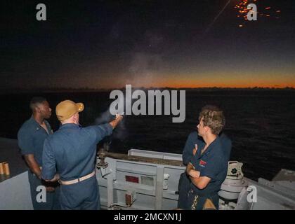 MARE DELLE FILIPPINE (11 luglio 2022) CMdR. Marcus Seeger, ufficiale comandante del cacciatorpediniere missilistico guidato della classe Burke di Arleigh USS Benfold (DDG 65) lancia un flare di prova dal ponte della nave. Benfold viene assegnato al Comandante, Task Force (CTF) 71/Destroyer Squadron (DESRON) 15, il più grande DESRON della Marina e la principale forza di superficie della flotta statunitense 7th. Foto Stock