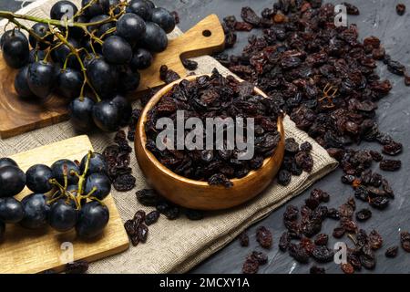 Uva passa nera essiccata in recipiente di legno, sfondo svuso. Messa a fuoco selettiva Foto Stock