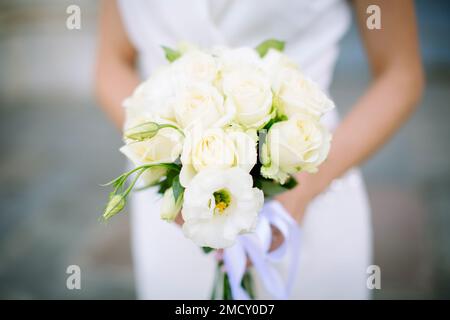 Bel bouquet fresco di rose e altri fiori in colori beige chiaro nelle mani della sposa. Messa a fuoco morbida, sfocatura dello sfondo. Foto Stock