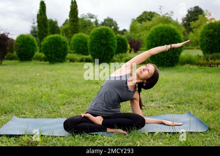 Donna caucasica, istruttore di yoga, fare tratto laterale, seduta curva laterale colonna vertebrale. Concetto di stile di vita sano. Foto Stock