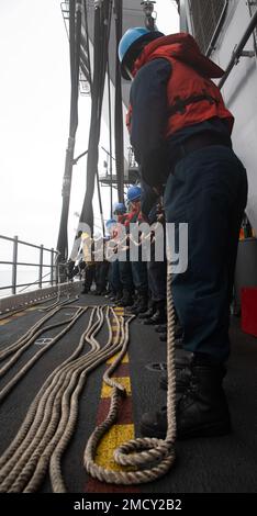 220712-N-XK047-1174 OCEANO PACIFICO (12 luglio 2022) – i marinai si preparano ad erigere la linea durante un rifornimento di carburante in mare con la nave portuale di trasporto anfibio USS John P. Murtha (LPD 26) sul ponte di volo della nave d'assalto anfibio USS Makin Island (LHD 8), Luglio 12 Makin Island è in grado di ricevere e fornire carburante ad altre navi per aiuti umanitari o per aiutare a sostenere altri beni militari durante una missione. Makin Island è attualmente in corso di svolgimento di operazioni di routine nella flotta degli Stati Uniti 3rd. Foto Stock