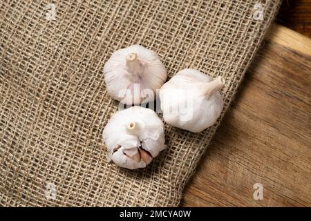 Tre teste di aglio secco su sfondo di legno. Foto Stock