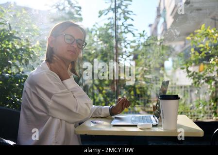 Architetto donna, laptop e dolore al collo in stress, burnout o lavoro eccessivo in ufficio. Dipendente caucasica che soffre di mal di collo, infiammazione Foto Stock