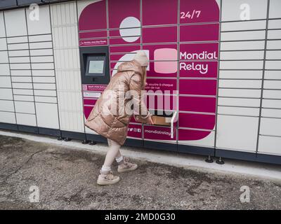 Loriol sur Drome, Francia - 14 gennaio 2023: Raccogliere un pacco da un Mondial `Relay Locker da una giovane donna. Relè Mondial degli armadietti. Scatola di prelievo. Foto Stock