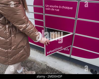 Loriol sur Drome, Francia - 14 gennaio 2023: Raccogliere un pacco da un Mondial `Relay Locker da una giovane donna. Relè Mondial degli armadietti. Scatola di prelievo. Foto Stock