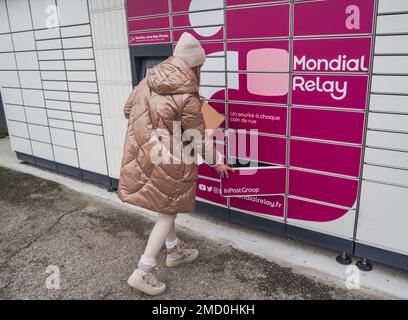 Loriol sur Drome, Francia - 14 gennaio 2023: Raccogliere un pacco da un Mondial `Relay Locker da una giovane donna. Relè Mondial degli armadietti. Scatola di prelievo. Foto Stock